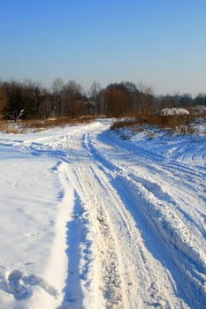 Snowy road between the meadows during wintertime