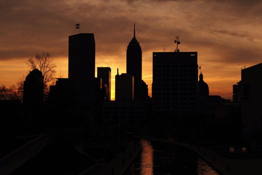Silhouette of skyscrapers set against a partly cloudy sky during sunrise.