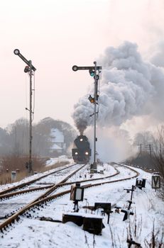 Old retro steam train starting from the station during wintertime