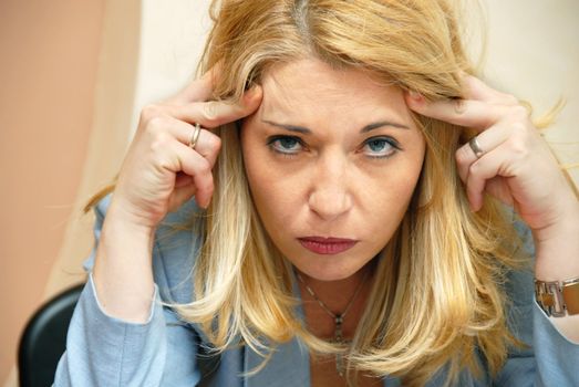 blond businesswoman suffering from headache indoor portrait