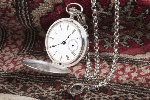 Elegant silver pocket watch over a carpet