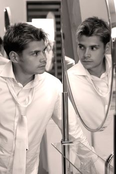 Young handsome man looking at himself in the mirror