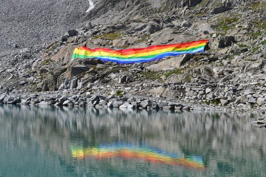 Peace flag dropped in mountain reflected in a lake, adamello Italy