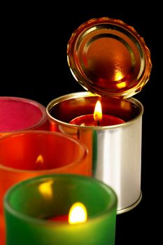 red candle on a tin can over black background