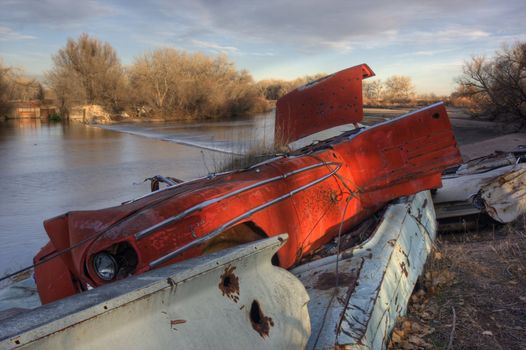 irrigation dam and old junk cars used to protect banks of South Platte River flowing through farmland of northern Colorado, late fall