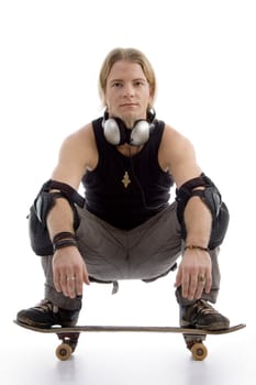 smart guy with headphones sitting on skateboard against white background