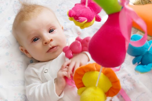 Three months old baby girl playing with toys