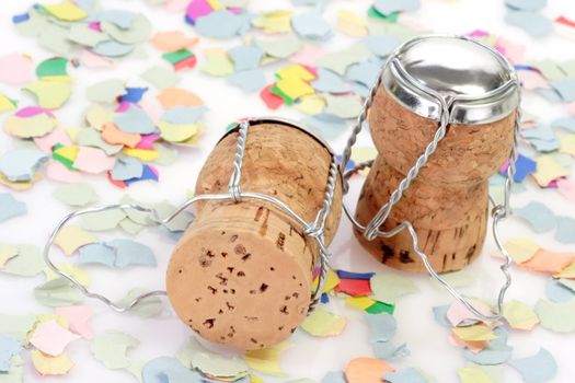 Two champagne corks and confetti on white background
