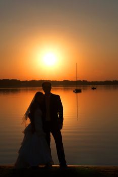 the young couple is standing after the marriage ceremony on the beach and cuddling 