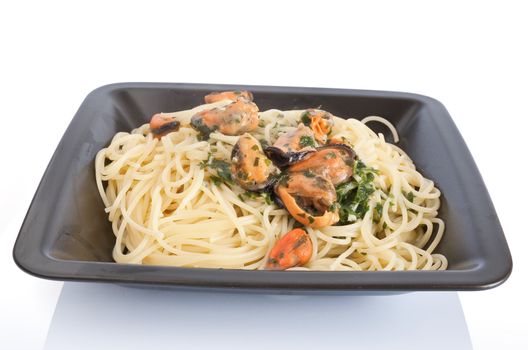 typical italian cooking: spaghetti with mussels and garlic. Plate isolated on white background with clipping path