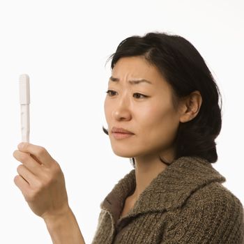Asian mid adult woman holding up pregnancy test.