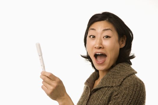 Asian mid adult woman holding up pregnancy test looking excited.