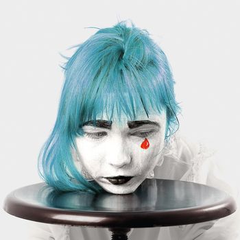 clown makeup girl with blue hair and red tear