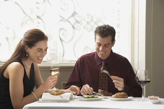 Mid adult Caucasian couple dining in restaurant and laughing.