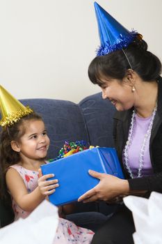 Mother giving daughter present at birthday party.