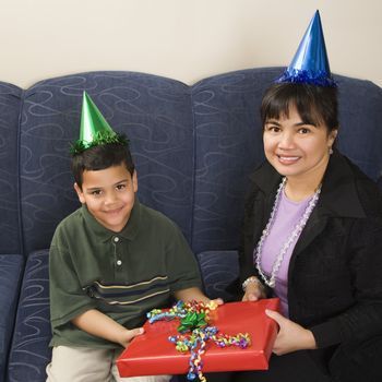 Mother and son wearing party hats holding birthday presents smiling and looking at viewer.
