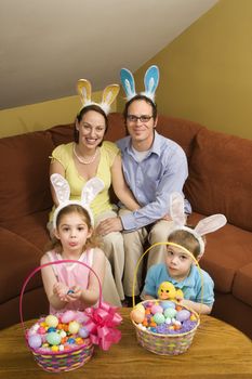Caucasian family wearing rabbit ears with Easter baskets looking at viewer.