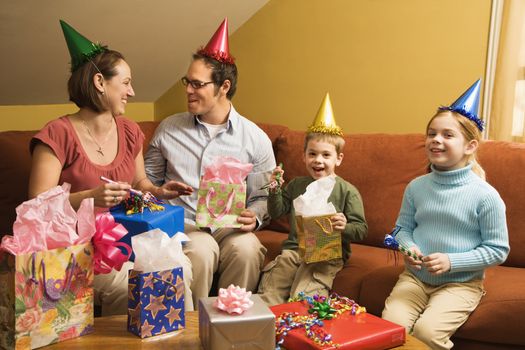 Caucasian family wearing party hats and celebrating a birthday party.