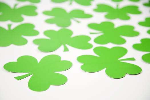 Group of green paper shamrocks on white.