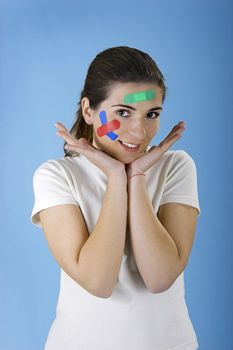 Beautiful woman with colored bandages on the face over a blue background