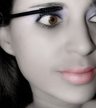 a young woman applying makeup to her eyes