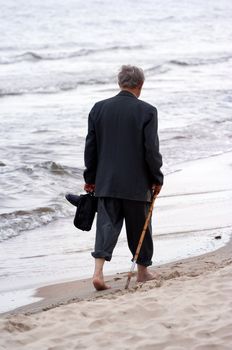 Old man is walking on beach 