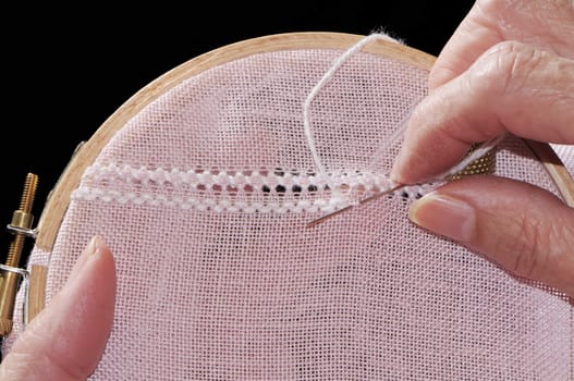 Woman hands embroidering a pink material