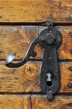 Close-up of an old iron handle on a wooden front door