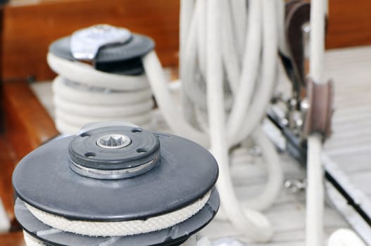 Detail of a winch with other equimpment of a sailboat in background