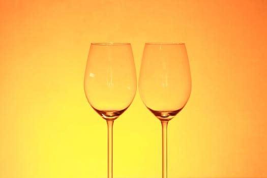 Two empty wineglasses isolated on gradient yellow background