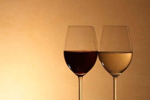 Closeup of two goblets with red and white wine on brown background
