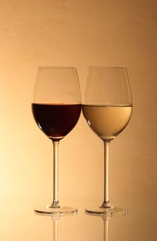 Two goblets with red and white wine on brown background