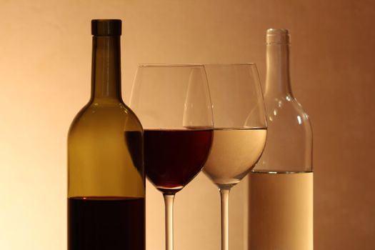 Pair of goblets and bottles with red and white wine on brown background