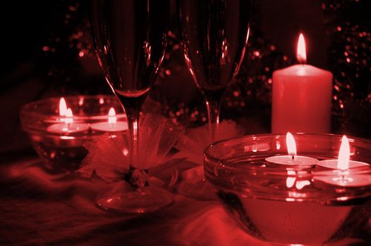 glasses of champagne, candles with christmas decorations, red toned