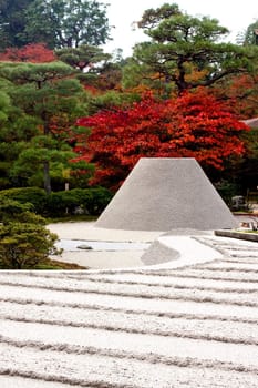 Red and green trees and a rock-garden in a Japanese autumn park 
