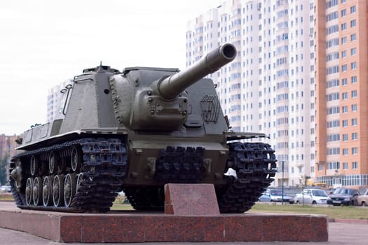 A memorial tank in a modern city in a cloudle day
