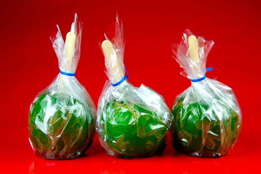 Green toffee apples isolated against a red background