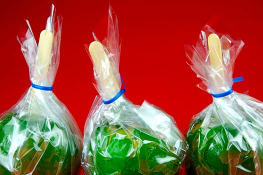 Green toffee apples isolated against a red background