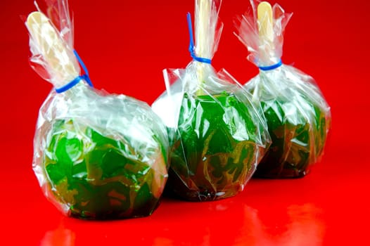 Green toffee apples isolated against a red background