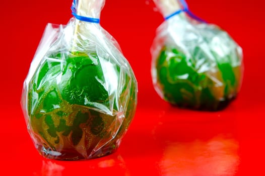 Green toffee apples isolated against a red background