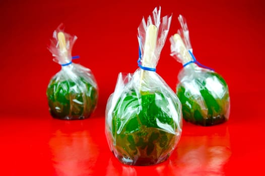 Green toffee apples isolated against a red background