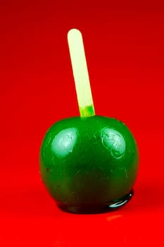 Green toffee apples isolated against a red background