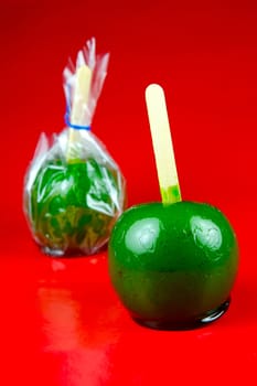 Green toffee apples isolated against a red background