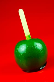 Green toffee apples isolated against a red background