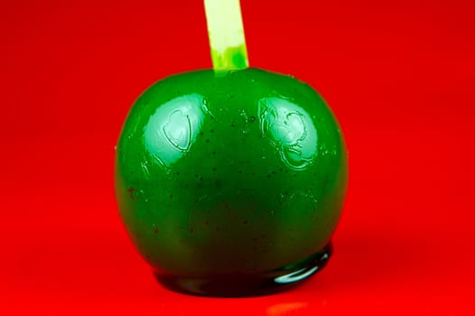 Green toffee apples isolated against a red background