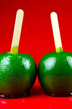 Green toffee apples isolated against a red background