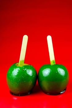 Green toffee apples isolated against a red background