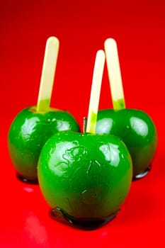 Green toffee apples isolated against a red background