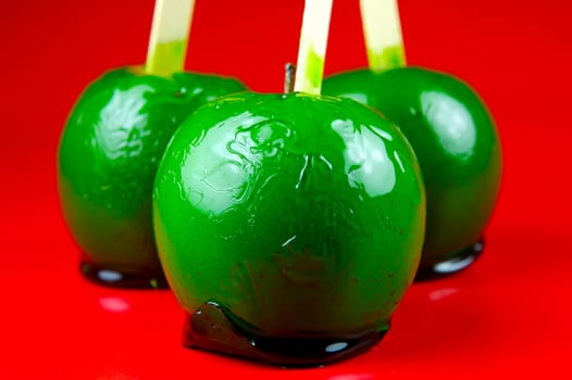 Green toffee apples isolated against a red background