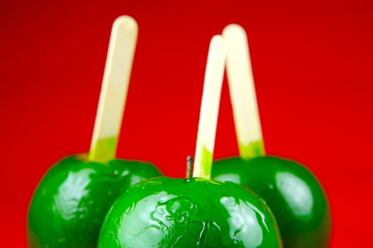 Green toffee apples isolated against a red background